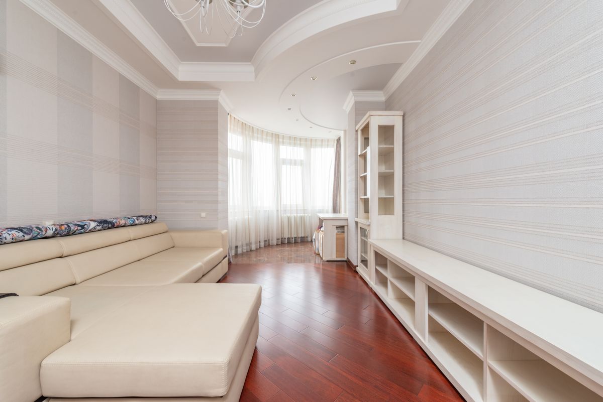 Sitting room with a smooth white multi-level ceiling, striped wallpaper, and built-in shelving